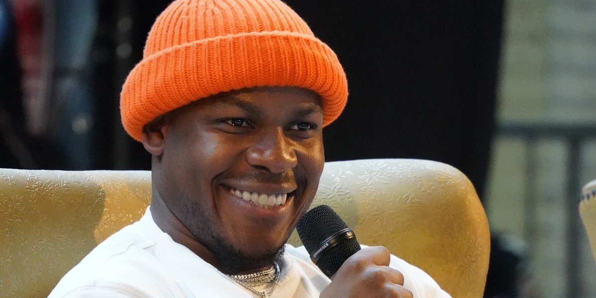 John Boyega smiling in an orange beanie at Brussels Comic Con 2025