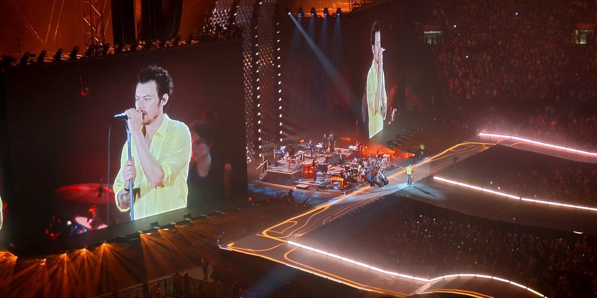 Harry Styles performing during his Together, Together tour concert in Amsterdam in 2026, shown on the venue's big screen