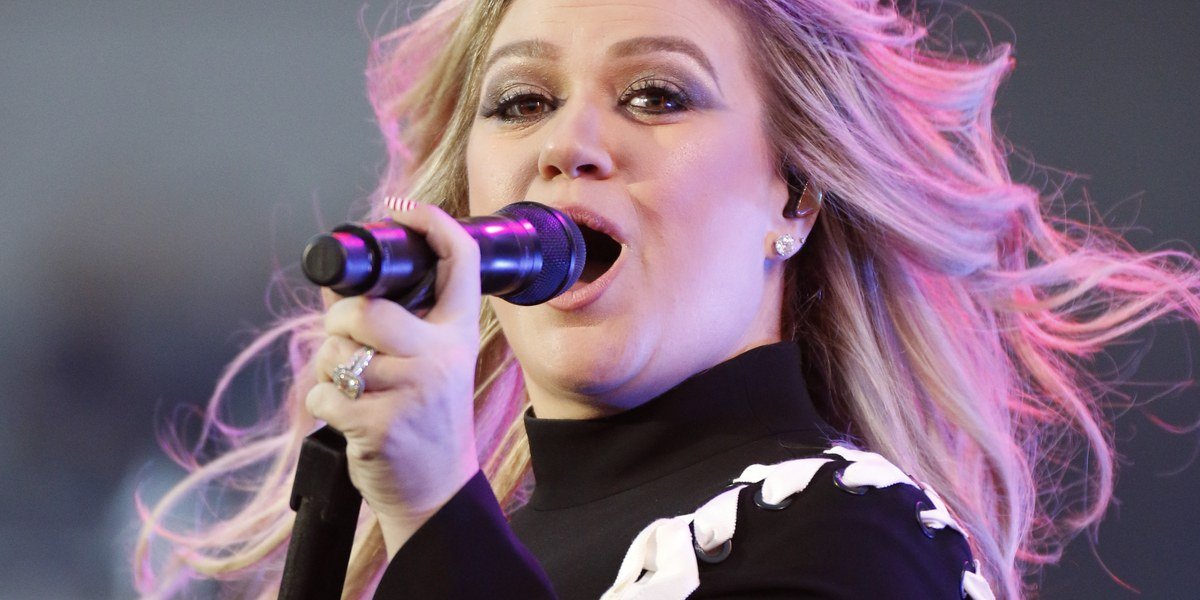Kelly Clarkson singing into a microphone at the 2018 DoD Warrior Games opening ceremony in Colorado Springs