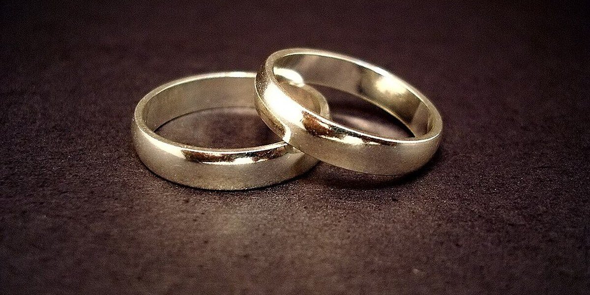 Two gold wedding rings resting on a dark surface