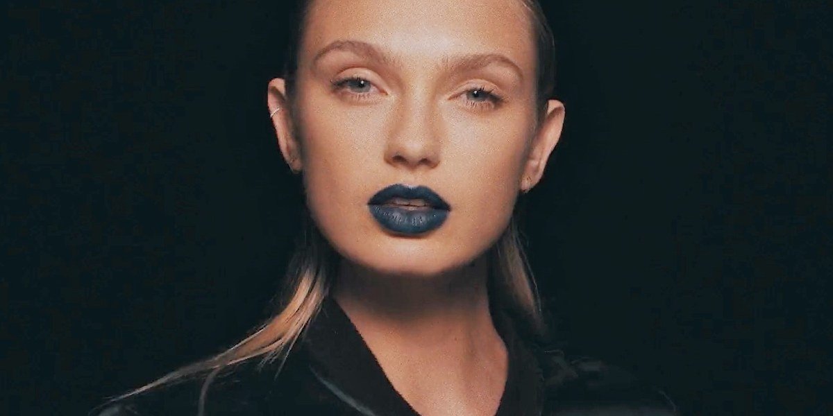 Close-up of Romee Strijd wearing dramatic dark blue lipstick in a fashion film shoot